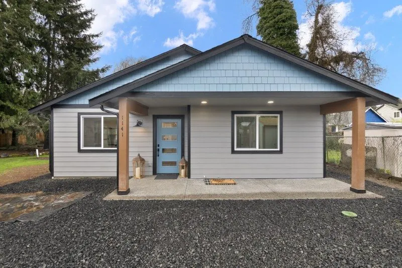 Single-story ADU with light blue siding and a blue front door built by Doyle Construction