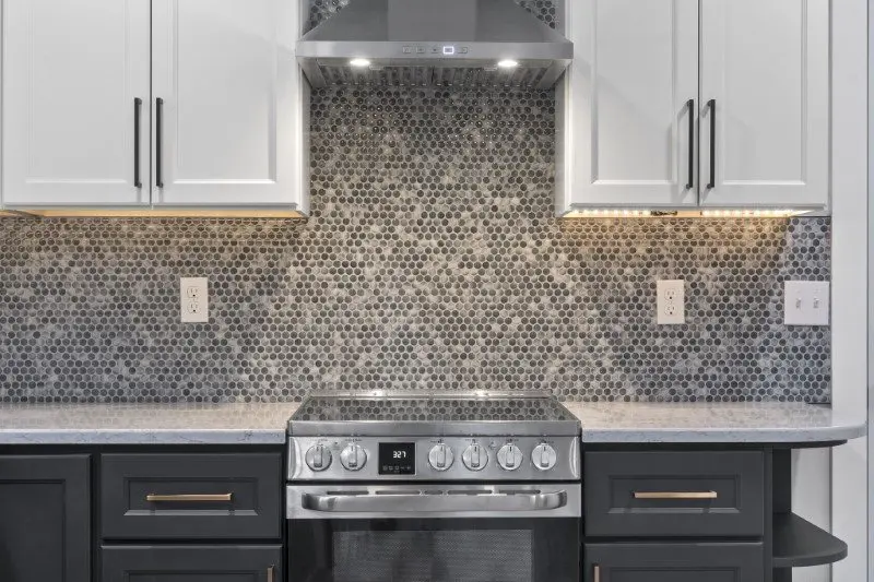 ADU kitchen with stainless stove and patterned tile backsplash