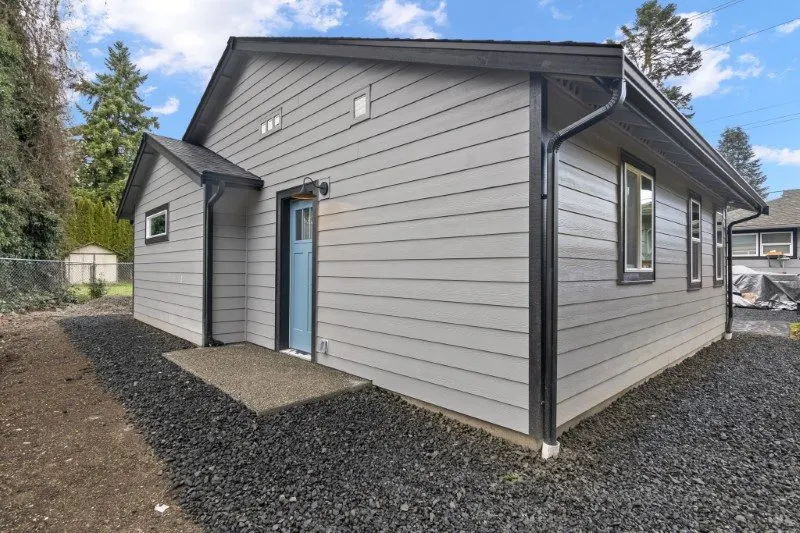 Single-story detached ADU with gray siding and a blue front door built by Doyle Construction