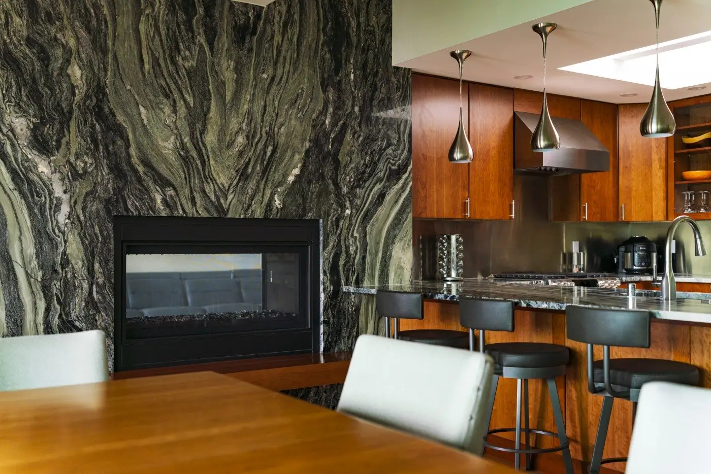 Remodeled kitchen and dining space with a dramatic natural stone fireplace wall at the Bayshore Remodel