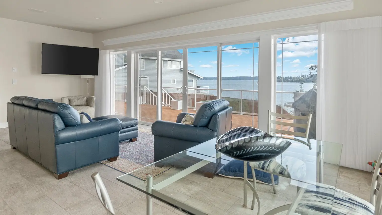 Modern living and dining space with large windows and a water view in a Doyle Construction custom home