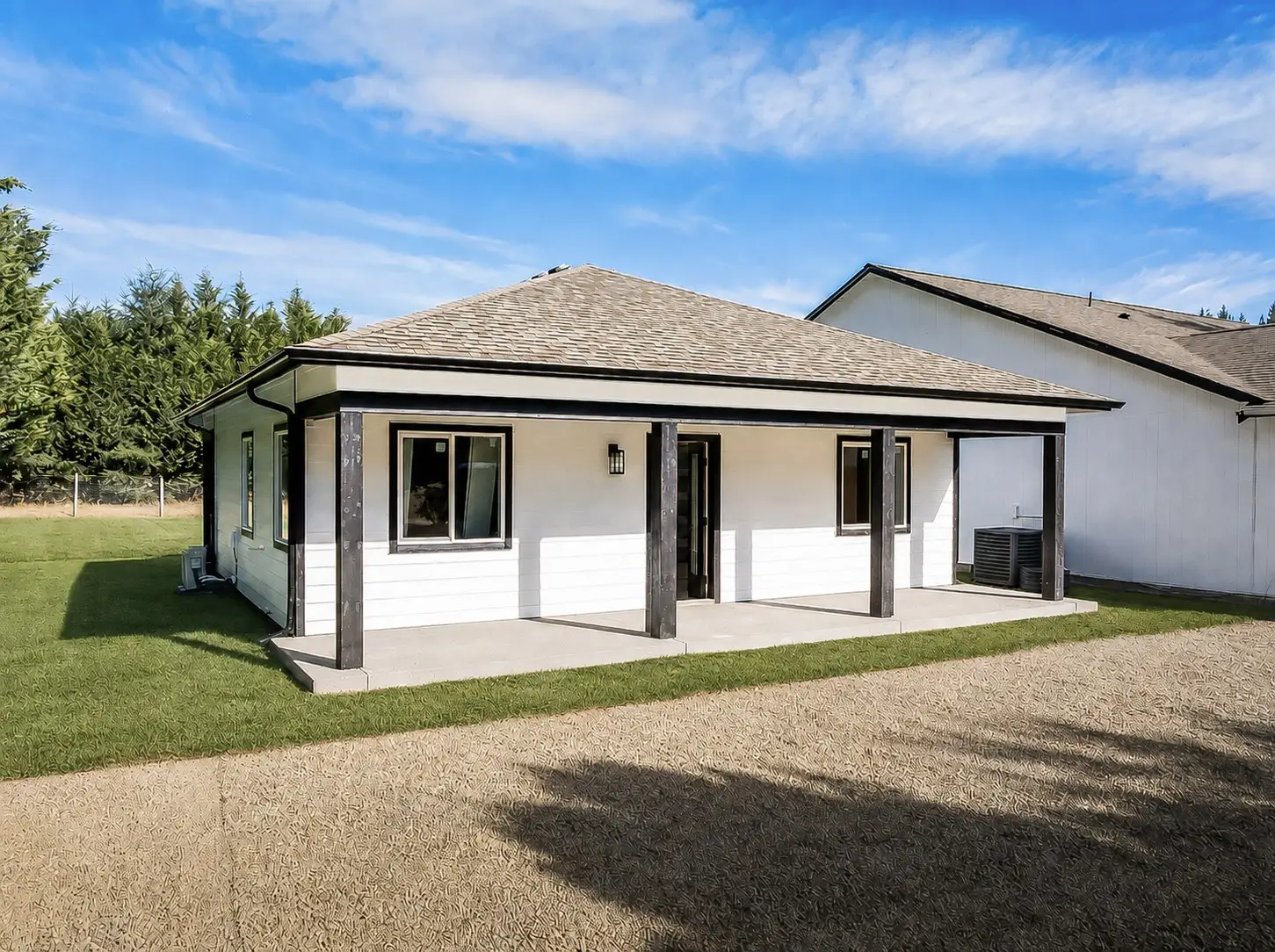 White single-story detached ADU with a covered porch and dark timber posts, built by Doyle Construction