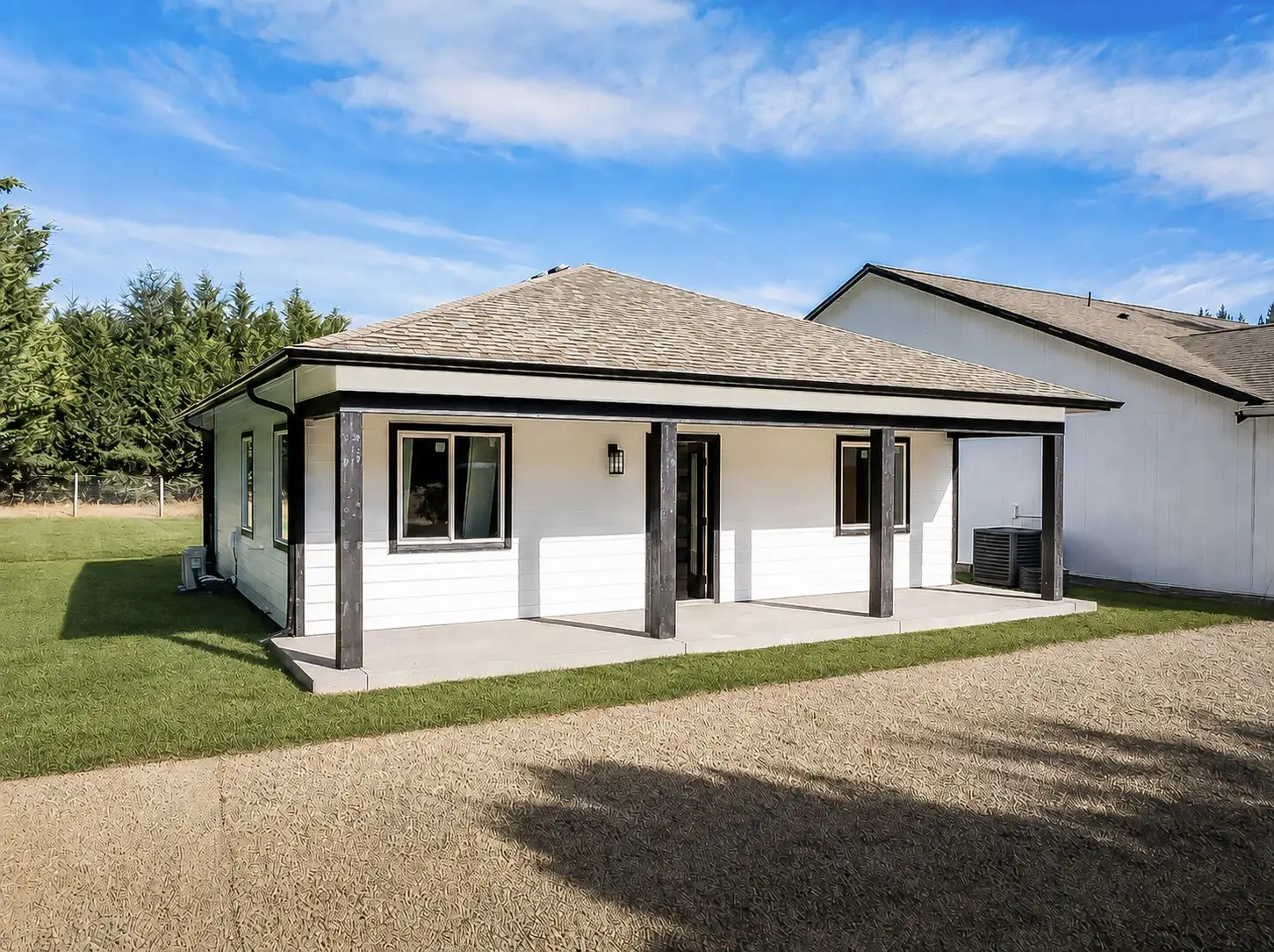 White single-story detached ADU with a covered porch and dark timber posts, built by Doyle Construction