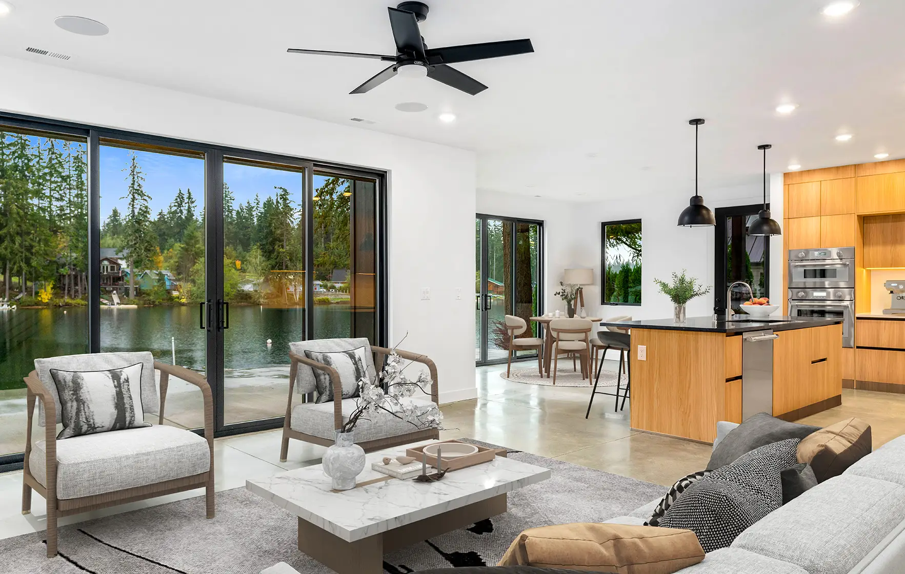 Open-plan living room and kitchen with glass doors overlooking Spencer Lake, a Doyle Construction custom home