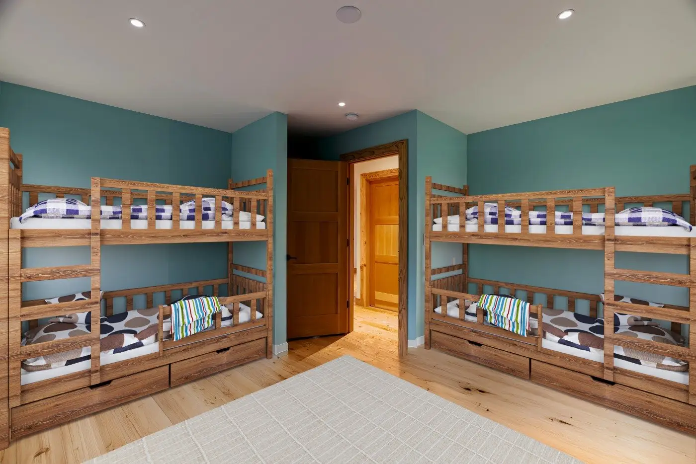 A bedroom with two wooden bunk beds, each with blue and white checkered bedding and pillows. The room has teal walls, a wooden floor, a beige rug, and an open wooden door leading to a hallway.