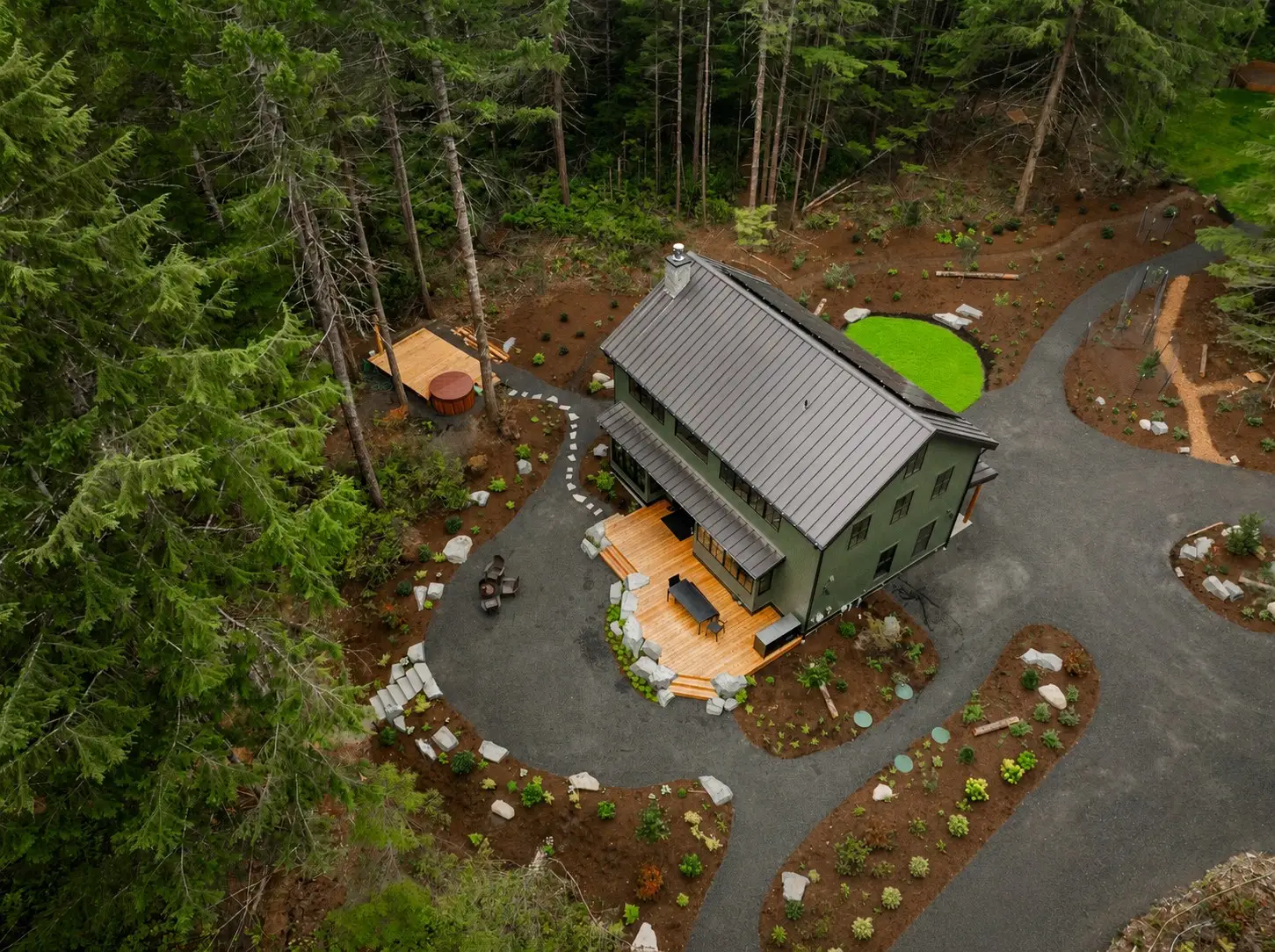 Aerial view of the Hatchery Lake Custom Cabin and its landscaped grounds among evergreens