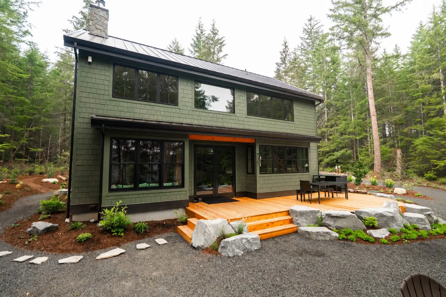 Back deck and forest-green shingle exterior of the Hatchery Lake Custom Cabin