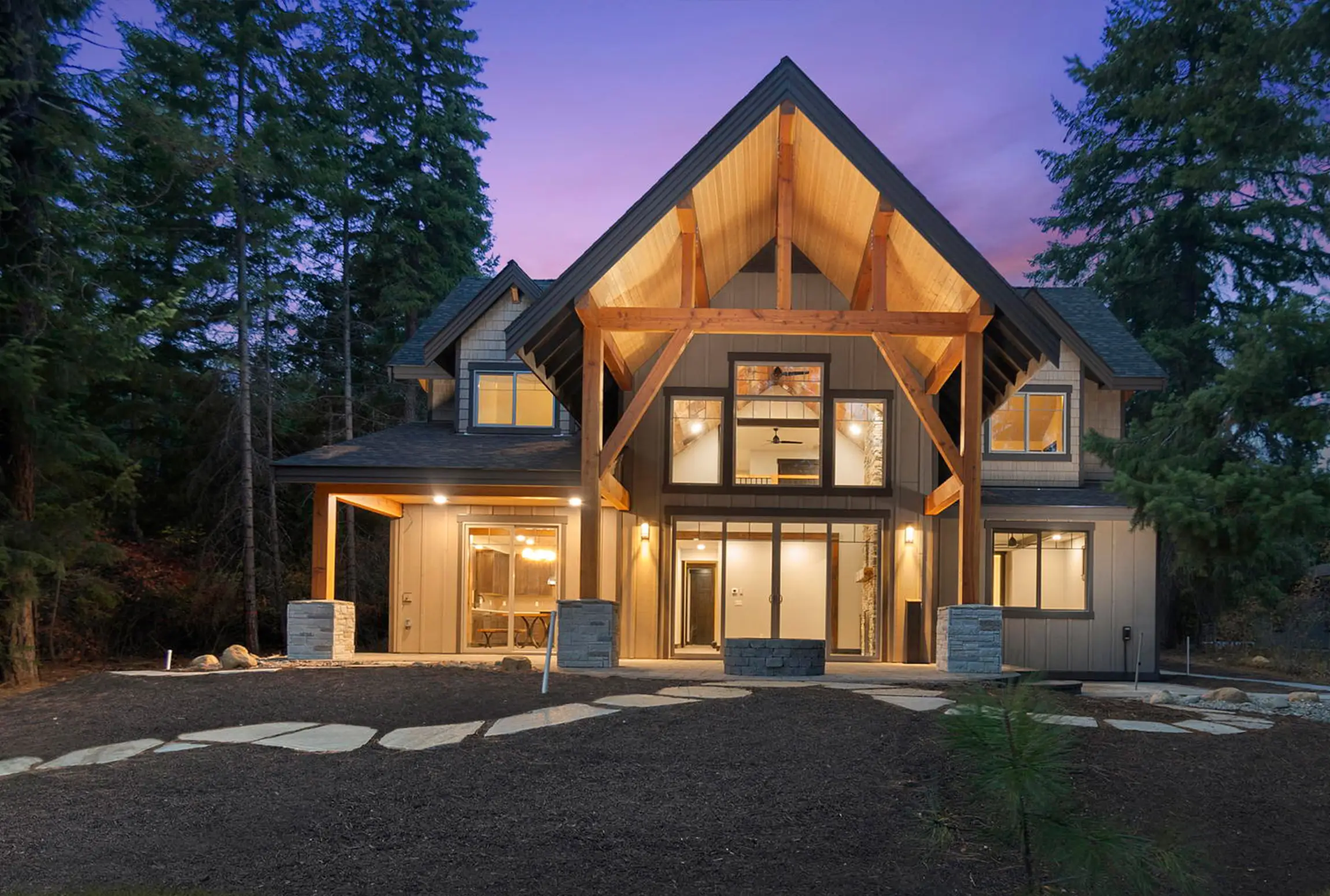 Two-story custom home with large windows and a peaked roof at dusk, built by Doyle Construction near Olympia