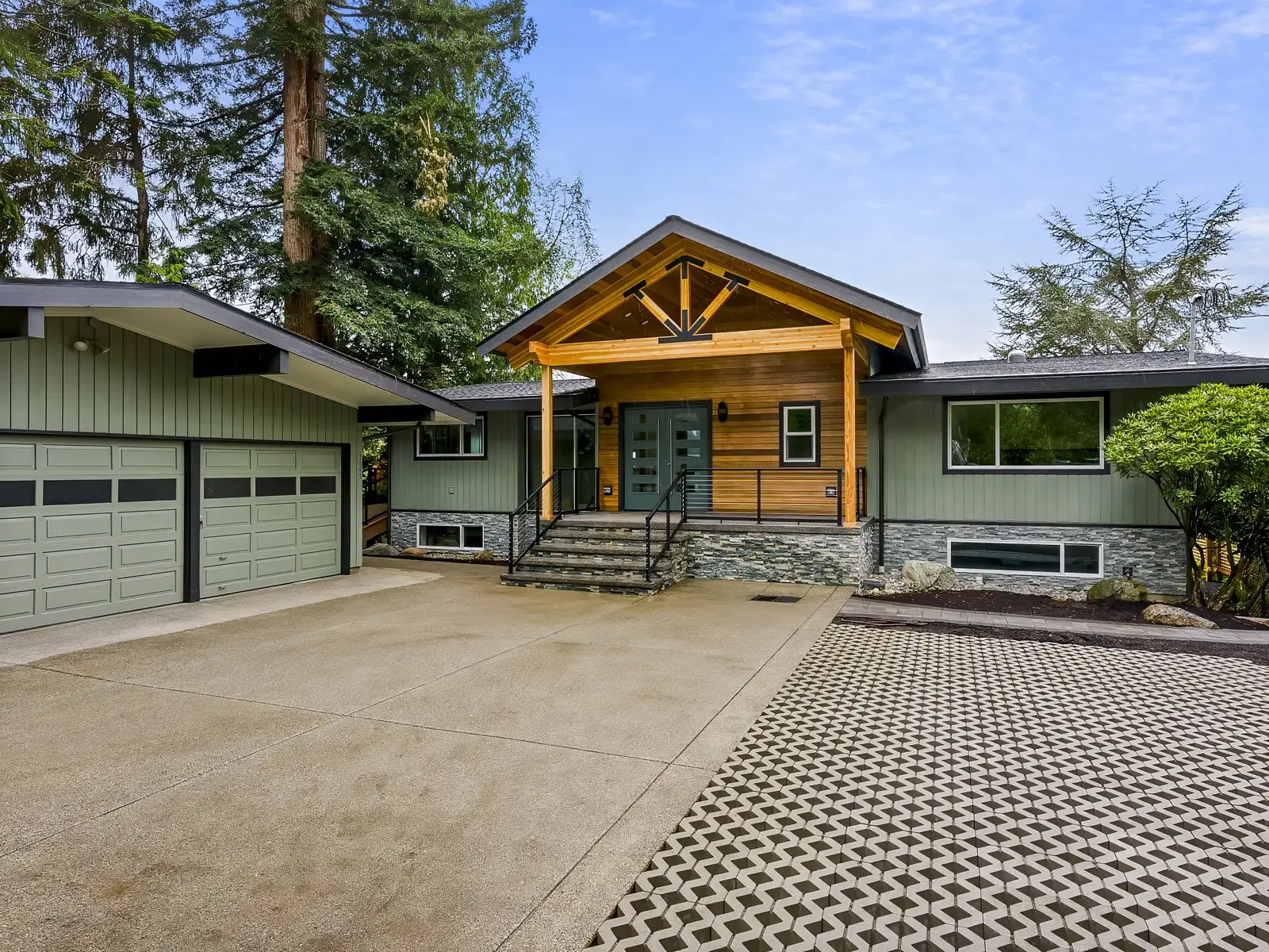 Green mid-century custom home by Doyle Construction with a timber-frame entry, stone accents, and patterned concrete driveway