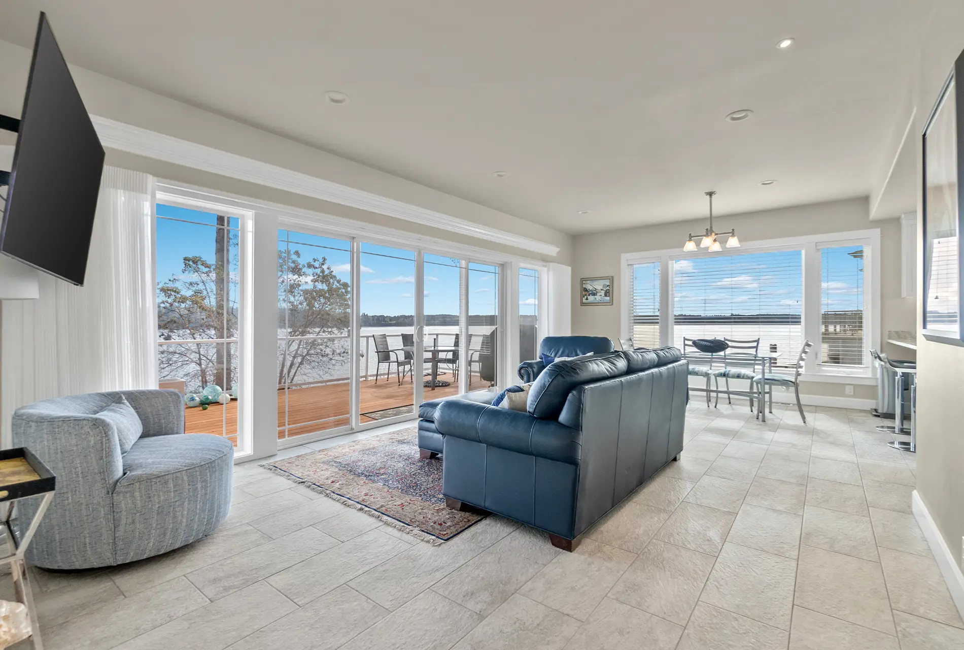 Bright remodeled living room with floor-to-ceiling windows opening to a wooden deck