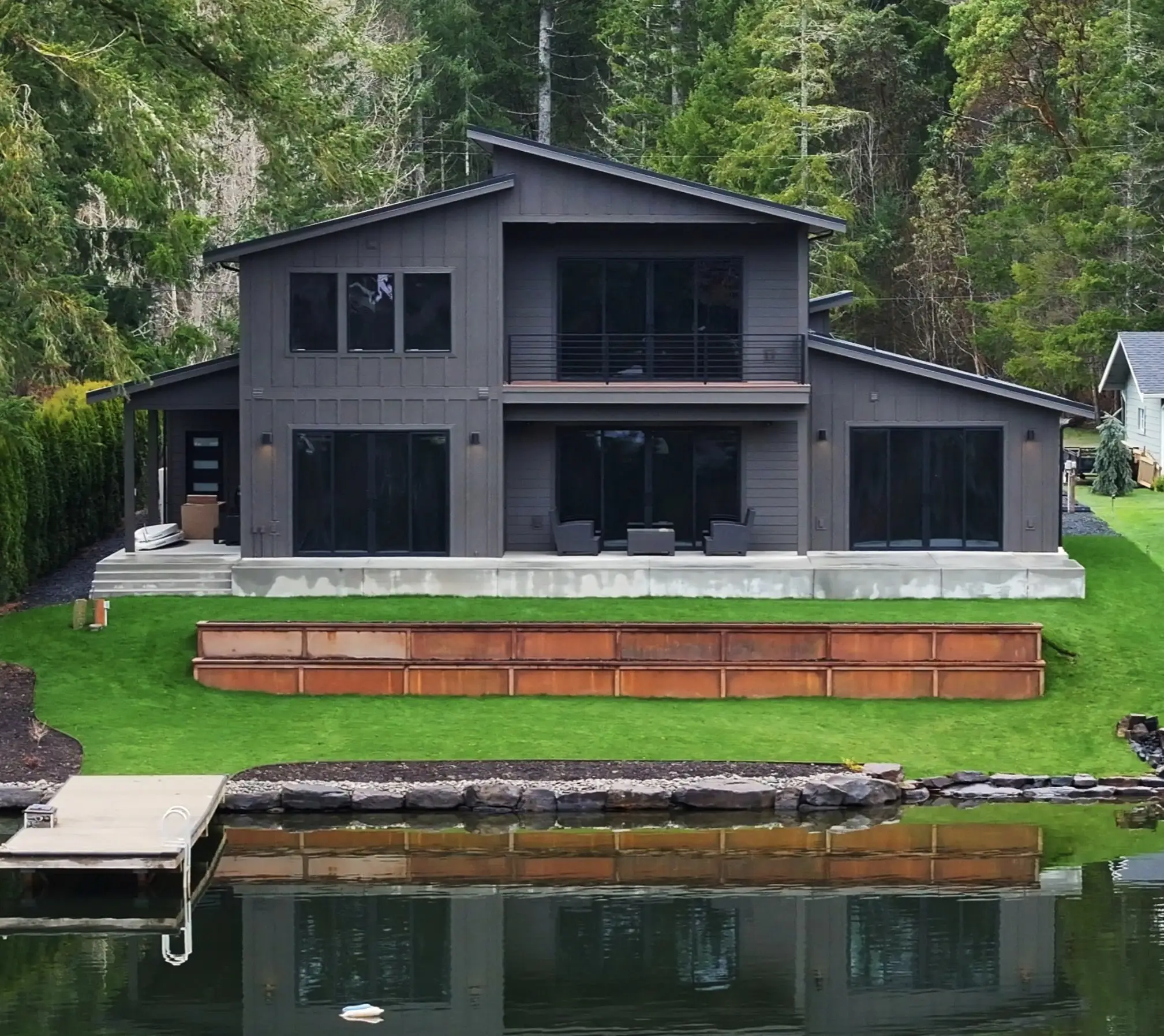 The Spencer Lake Custom home seen from the water, with dock and lakefront patio