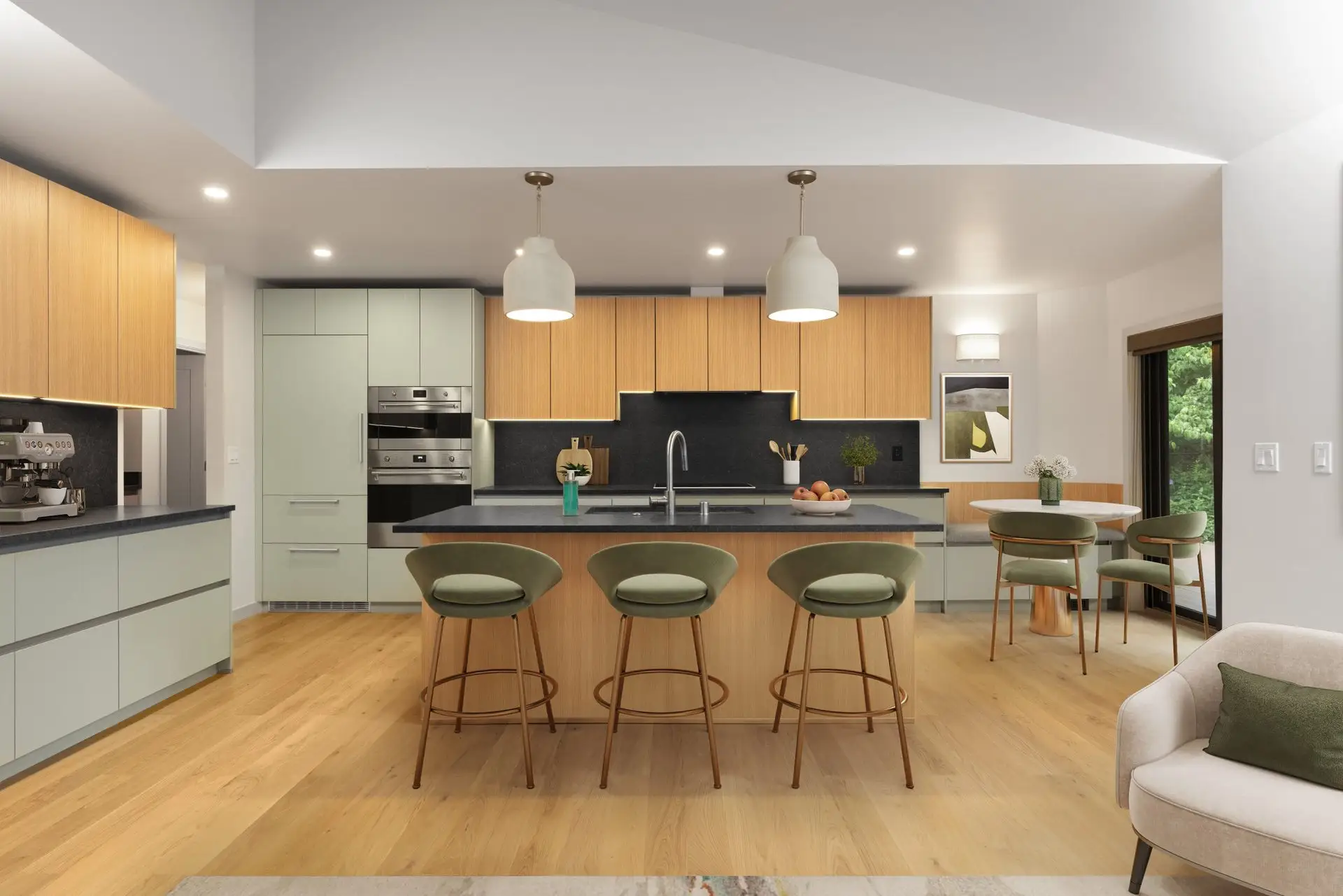 Modern kitchen with light wood floors, mint green cabinets, wood accents, a large island with gray countertop, three green barstools, pendant lights, and a dining table with green chairs by a window.